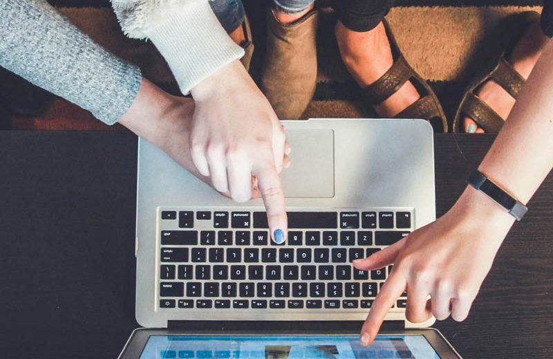 Team arbeitet am Laptop Drei Personen zeigen auf einen Laptop und optimieren eine Website.